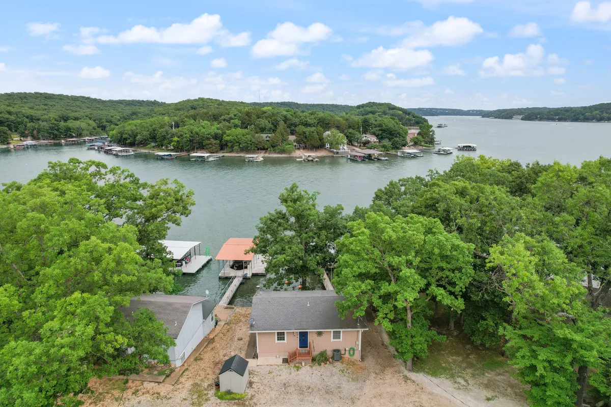 This image focuses on the house itself, positioned right by the waterfront among trees. The scene emphasizes the proximity of the home to the lake, with easy access for boating or fishing adventures.