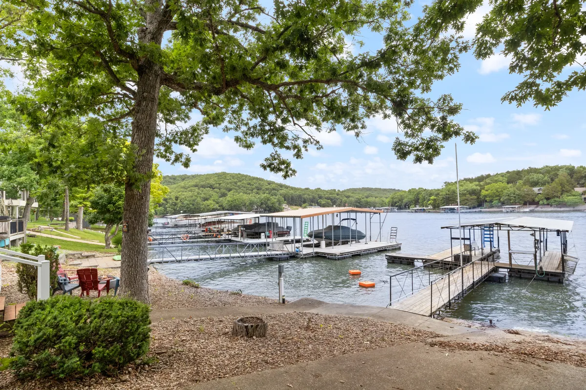 This image captures multiple lake docks and boathouses nestled among trees, with a seating area by the water. The setting feels tranquil and inviting, with the docks clearly accessible for boating and fishing activities.